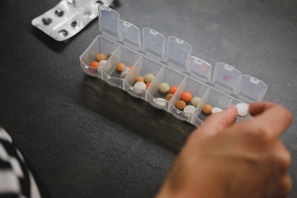 Image of person placing medication in pill box.