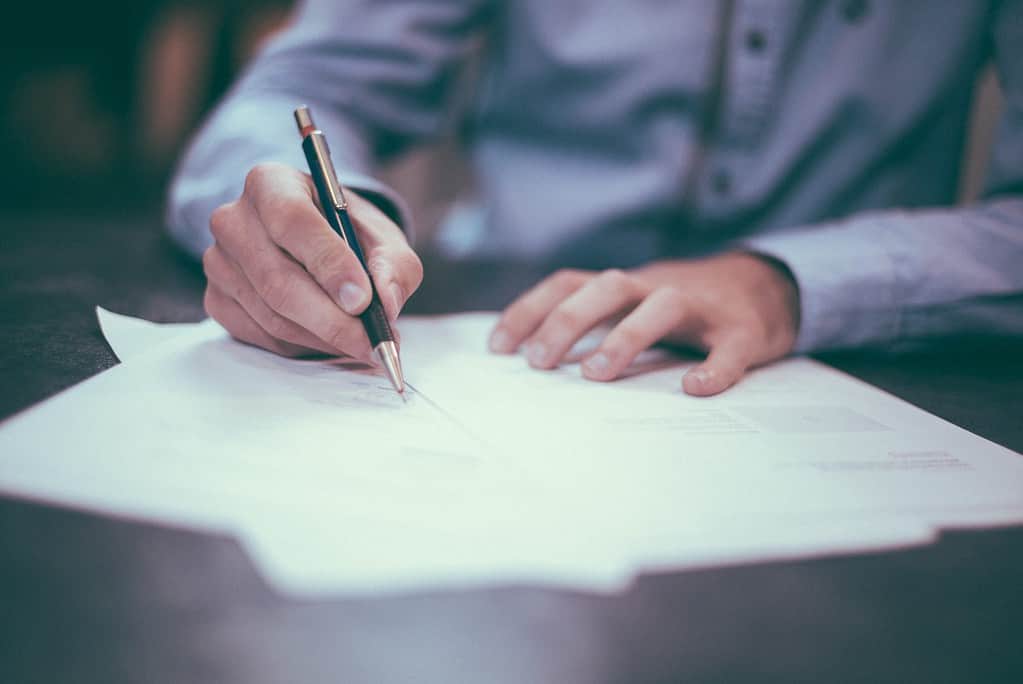 Image is of a man signing paperwork.