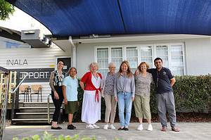 Six members at the Inala Family Support Centre stand under their vibrant new shade sail in the parking lot. The shade sail was purchased using a generous grant from Heritage Bank